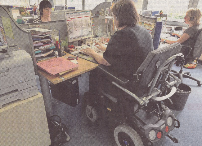 Rollstuhlfahrerin an einem Büroarbeitsplatz